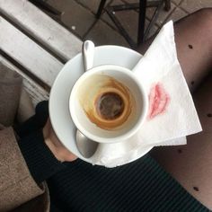 a person holding a cup of coffee on top of a white saucer and napkin