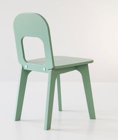 a green plastic chair sitting on top of a white floor in front of a wall