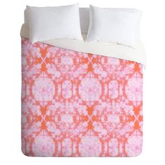 an orange and pink comforter with white pillows on the bottom, in front of a white background