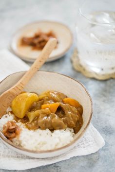 a bowl filled with rice and meat on top of a table next to a glass of water