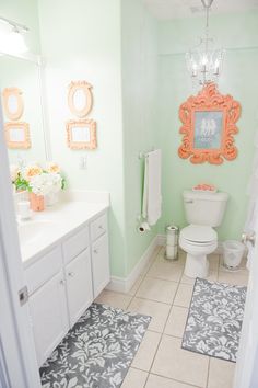 a bathroom with a toilet, sink and mirror in it's center wall is painted mint green