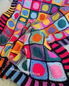 a crocheted blanket is laying on the couch with it's colorful colors