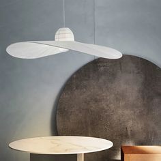 a table and chair in a room with a round light fixture hanging from the ceiling