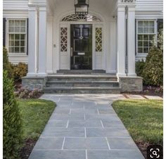 the front entrance to a white house with columns