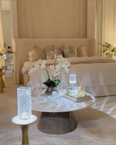 a white bed sitting next to a table with flowers on it