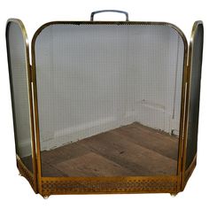 an old fashioned metal and wood fire place with mesh screen on the front, sitting on top of a hard wood floor