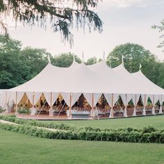 a large tent set up in the middle of a field with tables and chairs around it