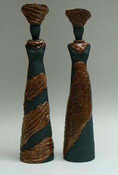 two decorative vases are sitting side by side on a white surface, one is green and the other is gold