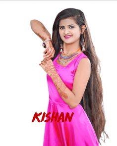 a woman in a pink dress holding a wooden stick with the words kishan written on it