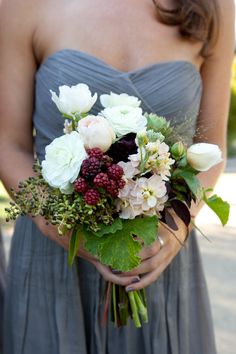 a bridesmaid holding a bouquet of flowers and greenery