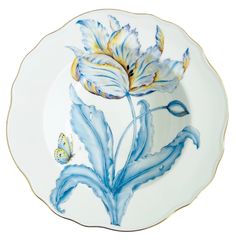 a white plate with blue and yellow designs on the rim, has a butterfly sitting on it