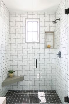 a bathroom with black and white tile on the floor, shower head, and window