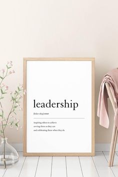 a framed poster with the words'leadership'on it next to a chair and flowers