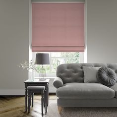 a living room with a gray couch and pink roller shades