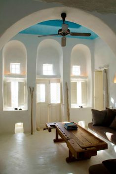 a living room with an arched ceiling and blue painted ceiling fan in the middle of it