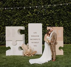 a bride and groom standing next to each other in front of large pieces of puzzle