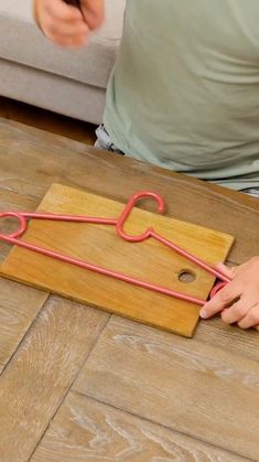 a person sitting on the floor with a pair of scissors in front of a piece of wood