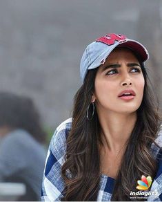 a woman with long hair wearing a hat and looking off to the side while sitting on a bench