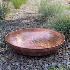 a large metal bowl sitting on top of gravel