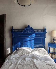 a bed with white sheets and blue headboard