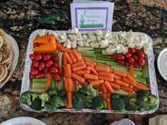 a tray filled with carrots, cauliflower and broccoli next to crackers