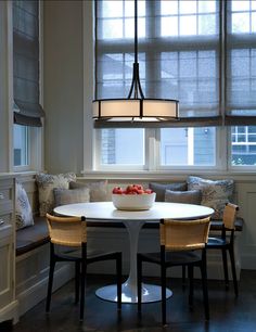 a dining room table with four chairs and a bowl of fruit on the center piece