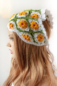 a woman with long hair wearing a white crocheted headband that has yellow flowers on it