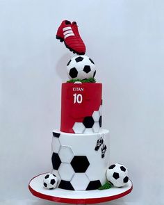 a three tiered cake decorated with soccer balls and adidas's boots on top