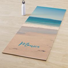 a beach scene with the name monica on it and a water bottle next to it