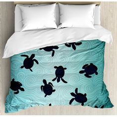 a bed with a blue and black turtle pattern on the comforter, pillows and pillow cases