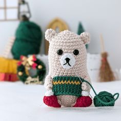 a crocheted teddy bear sitting on top of a bed