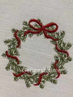 an embroidered christmas wreath with red ribbon