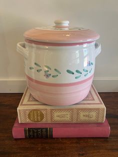 a pink and white casserole sitting on top of a book next to a wall