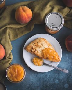 a piece of pie on a white plate next to some peaches and jams