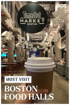 a person holding up a cup of coffee in front of a sign that says boston food hall