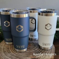 three yeti mugs sitting on top of a wooden table