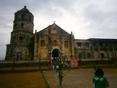 people are walking in front of an old church