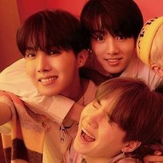 four young men are posing together for a photo in front of a red wall and one has his arm around the other man's shoulder