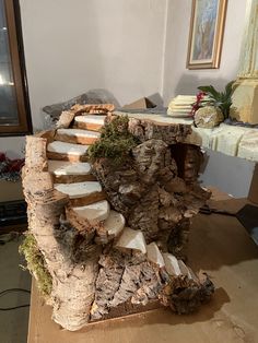 a wooden structure with steps made out of wood and moss growing on the sides, sitting on top of a table