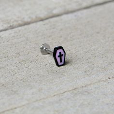 a pair of black and pink earrings with a cross on them sitting on concrete surface