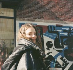 a woman standing in front of a graffiti covered building