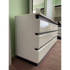 a white dresser sitting in front of a mirror on top of a carpeted floor