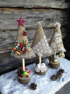 three small christmas trees made out of burlocks and pine cones in the snow