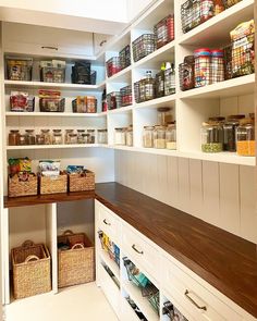 an organized pantry with white shelving and wooden shelves