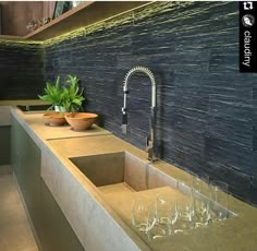 a modern kitchen with two sinks and wine glasses on the counter top next to it