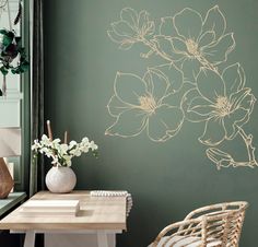 a vase with flowers sitting on a table next to a wall painted in green and gold