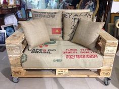 a chair made out of wooden pallets with pillows on it and other items in the background