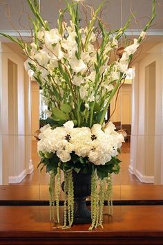 a vase filled with white flowers on top of a wooden table