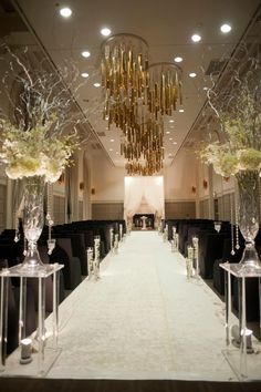 the aisle is lined with clear glass vases and flowers, along with tall centerpieces