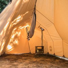 the inside of a tent that is set up in the woods with an open door